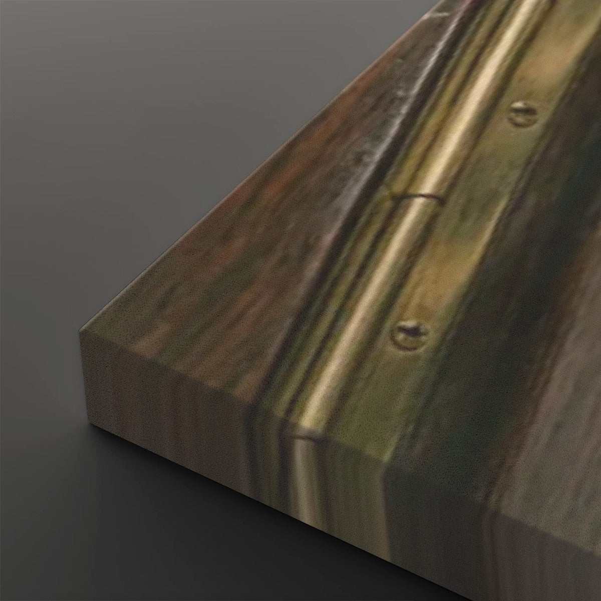A close-up of a wooden panel or door edge with a brass or bronze metal hinge strip and visible screws, photographed on a dark gray background.