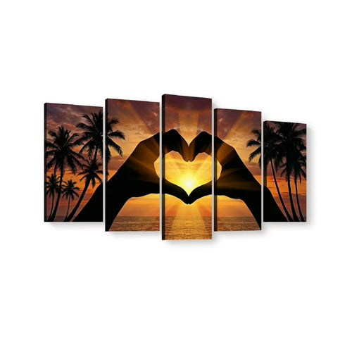 Five-panel canvas wall art showing a sunset beach scene with palm tree silhouettes and two hands forming a heart shape over the sun, displayed against a white background.