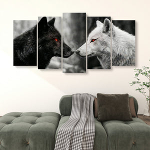 A 4-panel canvas wall art set depicting a black wolf with glowing red eyes facing a white wolf, displayed above a green sofa in a living room setting.