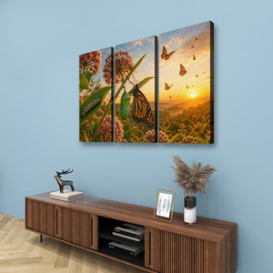 Three-panel canvas wall art depicting a monarch butterfly and wildflowers at sunset, displayed on a light blue wall above a wooden console table with decorative items.