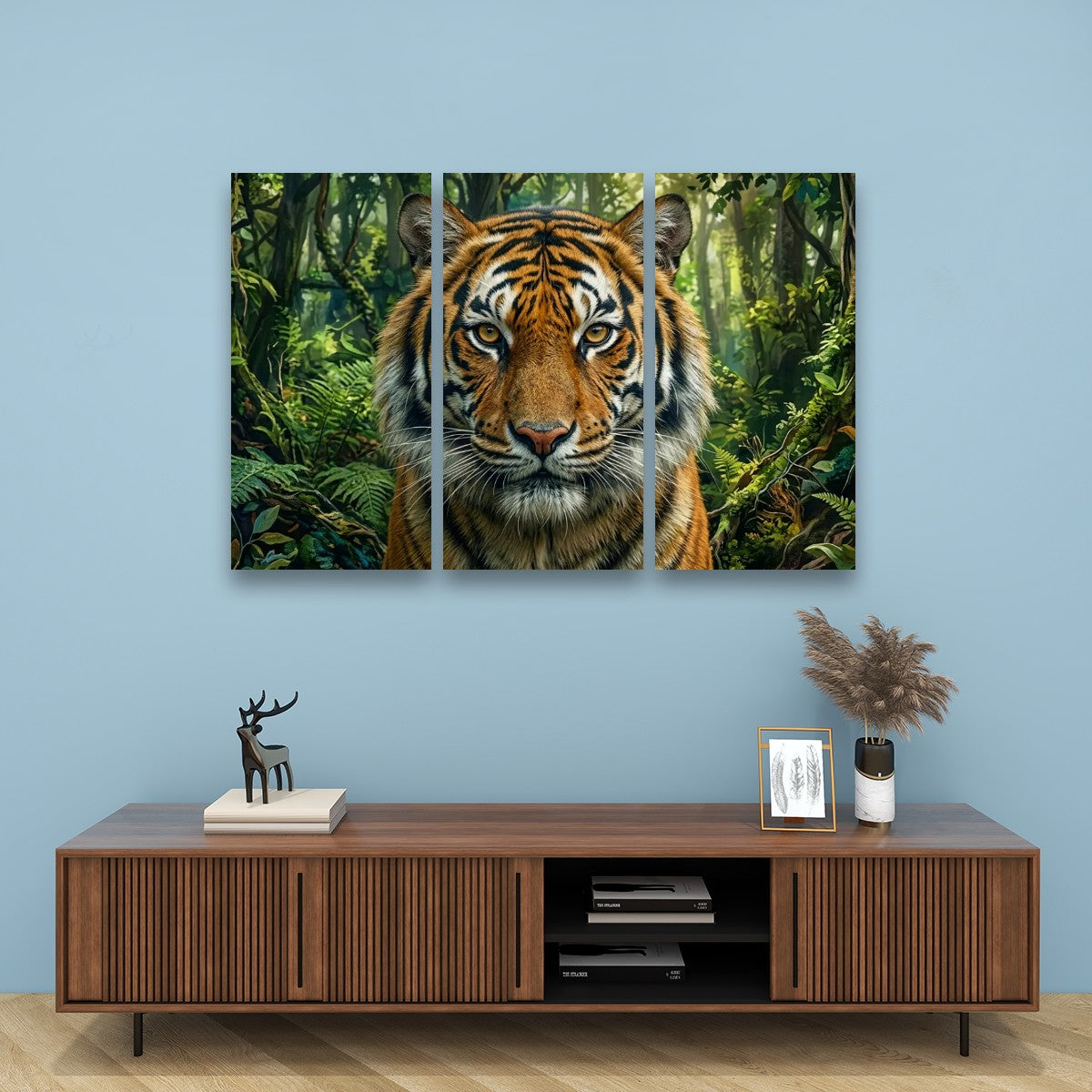 A three-panel canvas wall art set depicting a close-up tiger in a lush green jungle, displayed on a light blue wall above a wooden console table with decorative items.
