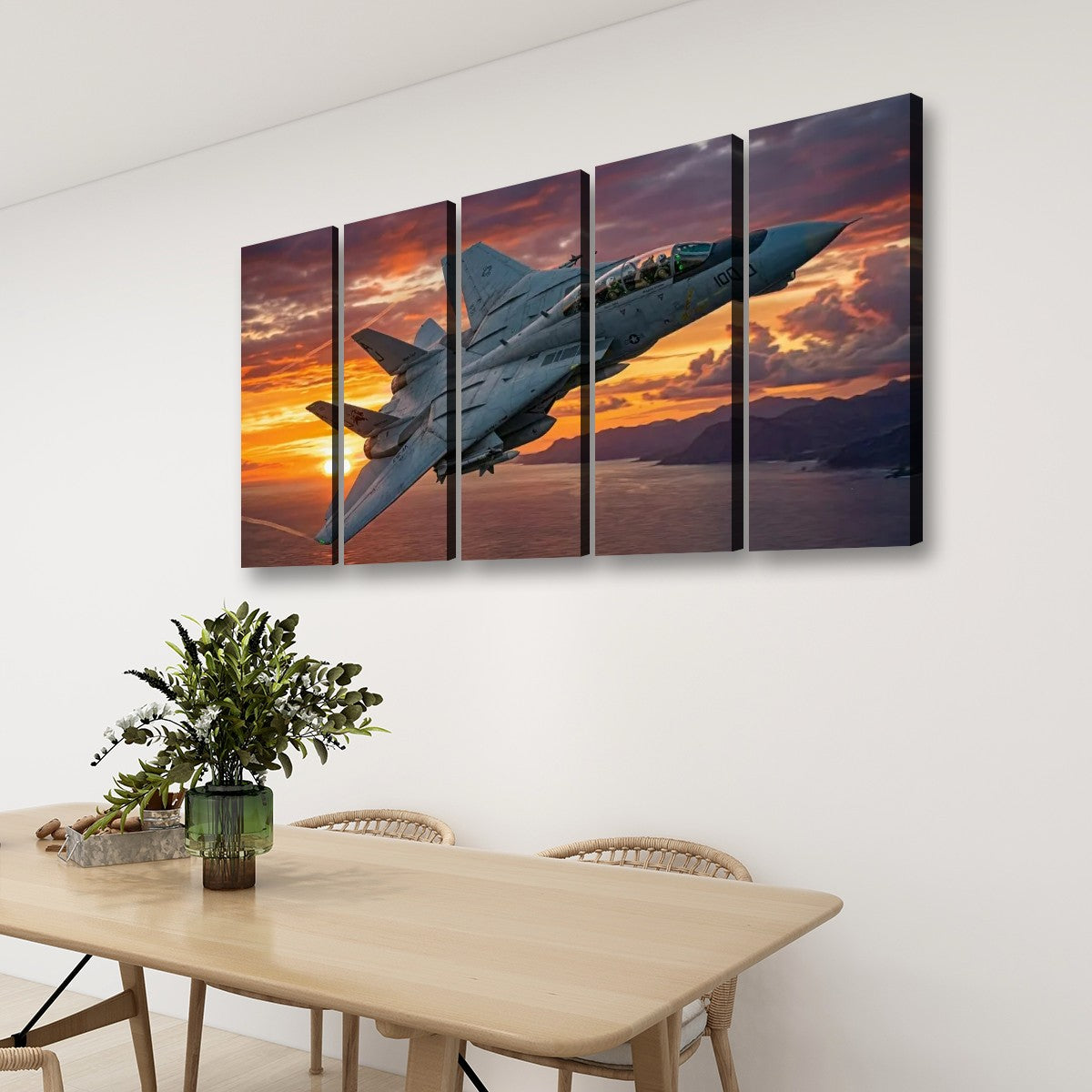 A four-panel canvas wall art set depicting a gray Grumman F-14 fighter jet flying over a sunset landscape, displayed on a white wall above a wooden dining table with chairs and a plant.