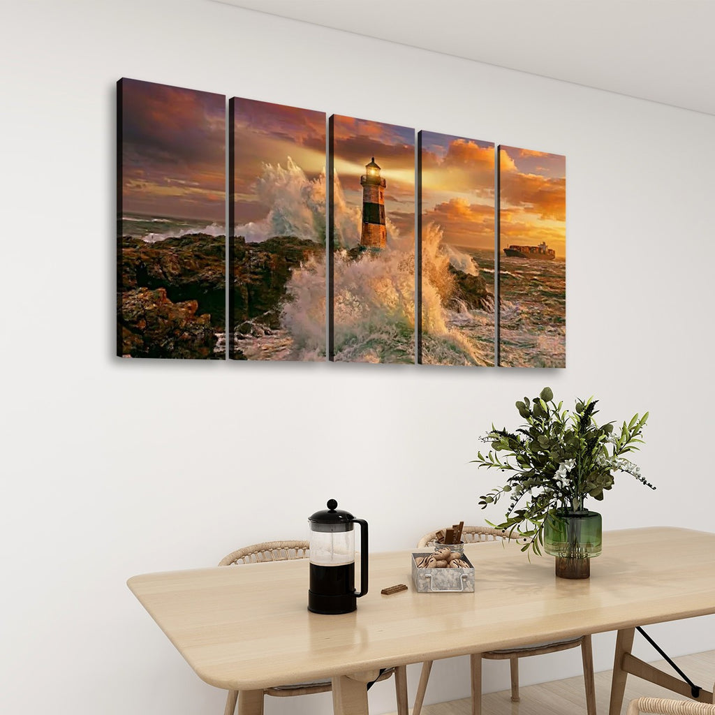 A five-panel canvas wall art set depicting a dramatic lighthouse scene at sunset, displayed on a white wall above a light wood dining table with a plant and coffee maker.