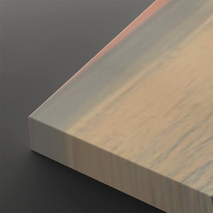 A close-up of a rectangular panel or board corner showing a light beige to off-white woodgrain or laminate surface with a smooth finish, photographed against a dark gray background.