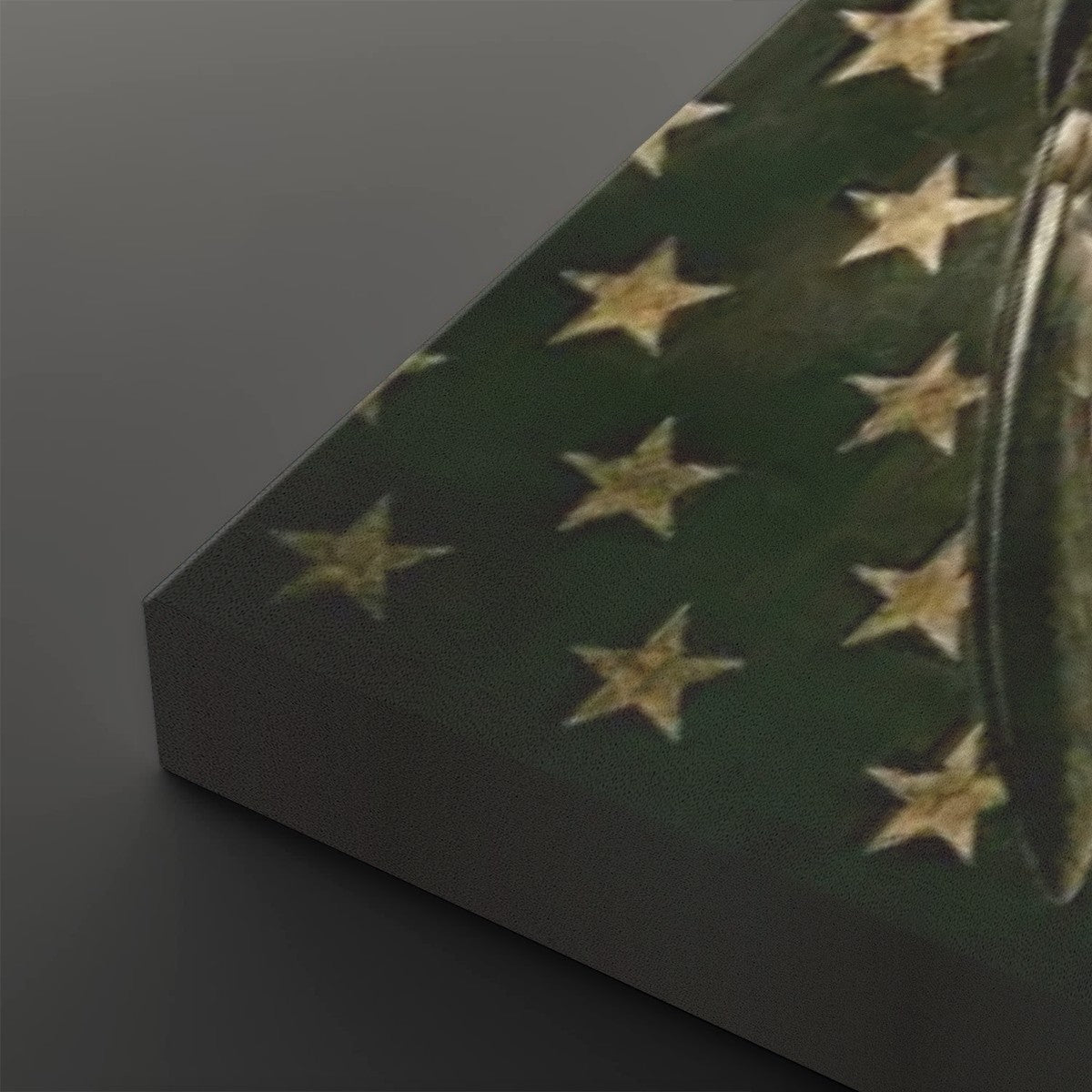 A close-up of a rectangular product, likely a box or package, showing a dark green surface with a pattern of gold stars, photographed on a dark gray background.