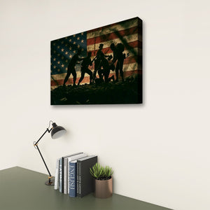A rectangular wall art print showing silhouetted soldiers in front of a distressed American flag, displayed on a light wall above a desk with a lamp, books, and a small plant.