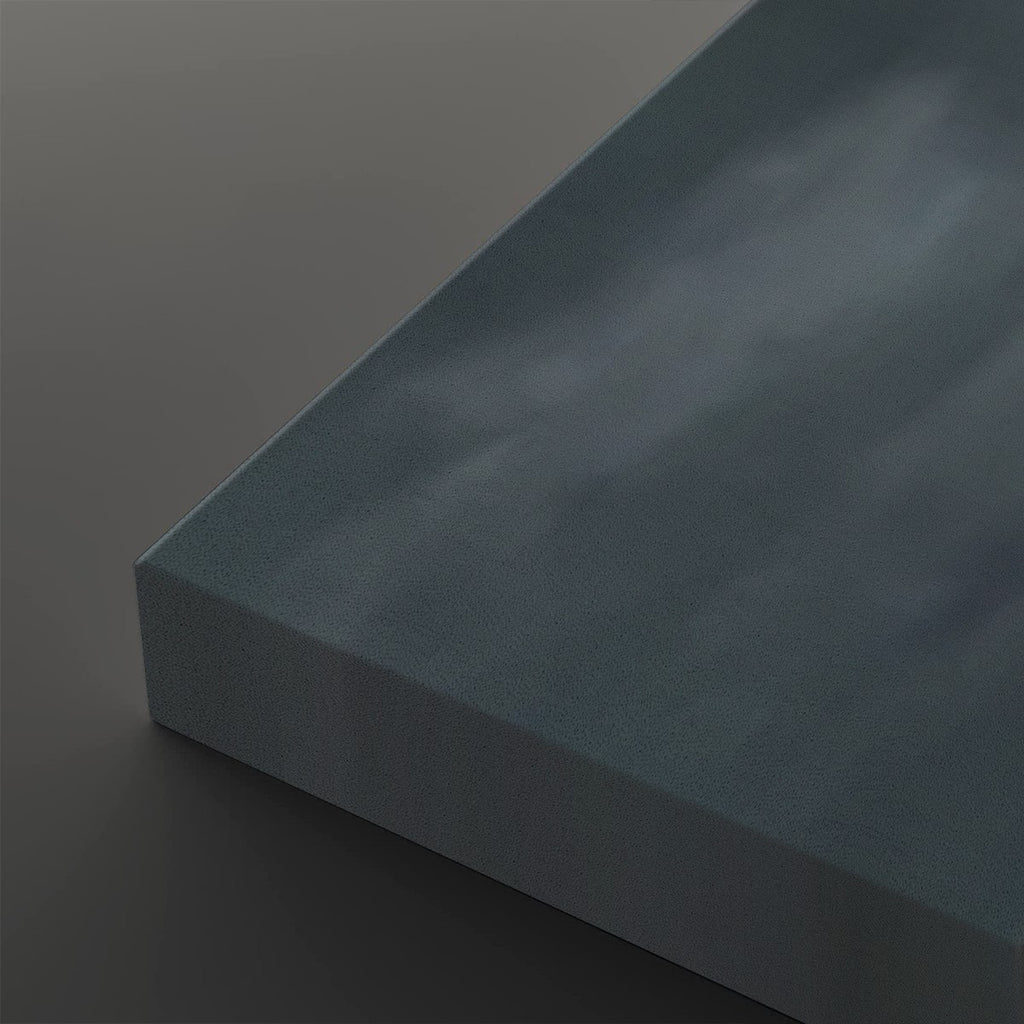 A close-up of a rectangular canvas or panel with a textured, cloudy blue-gray surface, shown at an angle against a dark gray background.