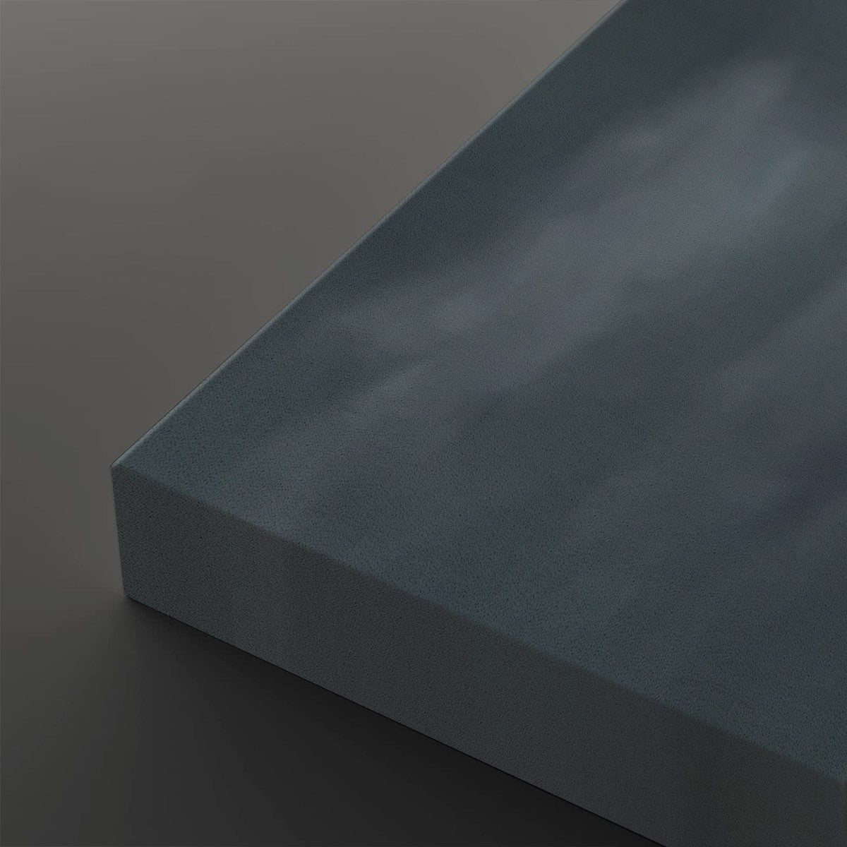 A close-up of a rectangular canvas or panel with a textured, cloudy blue-gray surface, shown at an angle against a dark gray background.