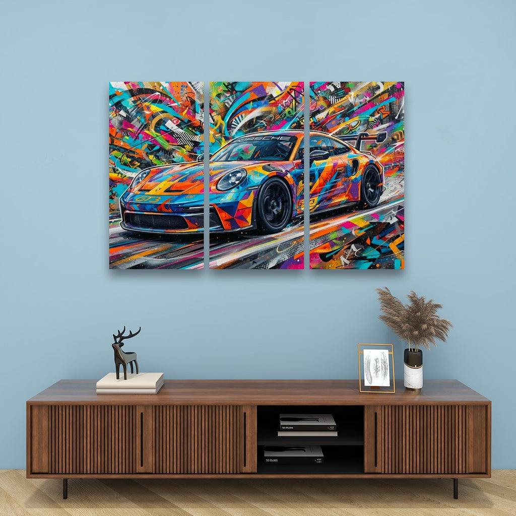 A three-panel canvas wall art print depicting a colorful, abstract Porsche 911 sports car, displayed on a light blue wall above a wooden media console with decorative items.