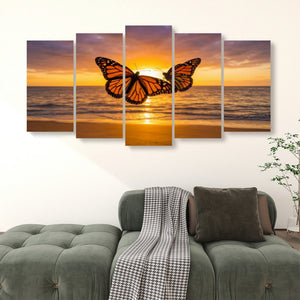 A five-panel canvas wall art set depicting a monarch butterfly over a sunset ocean scene, displayed above a green sofa in a living room setting.