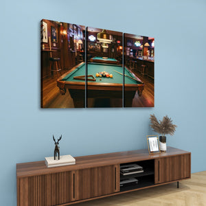 A three-panel canvas wall art print depicting a pool table in a dimly lit bar, displayed on a light blue wall above a wooden console table with decorative items.