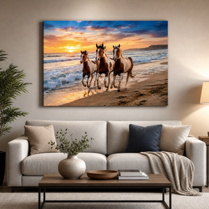 A large rectangular wall art print showing three horses running along a beach at sunset, displayed above a light beige sofa in a styled living room with pillows, a coffee table, and a plant.