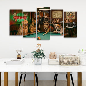 A five-panel canvas wall art set depicting playful dogs playing pool in a bar, displayed on a white wall above a modern white dining table with books, a vase, and baskets.