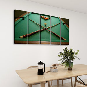 A five-panel canvas wall art set depicting a green pool table with crossed cues and billiards, displayed on a white wall above a light wood dining table with a vase of greenery and a coffee press.