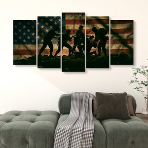 A 5-panel canvas wall art set depicting the silhouette of soldiers carrying a wounded warrior against a distressed American flag, displayed on a wall above a green sofa.