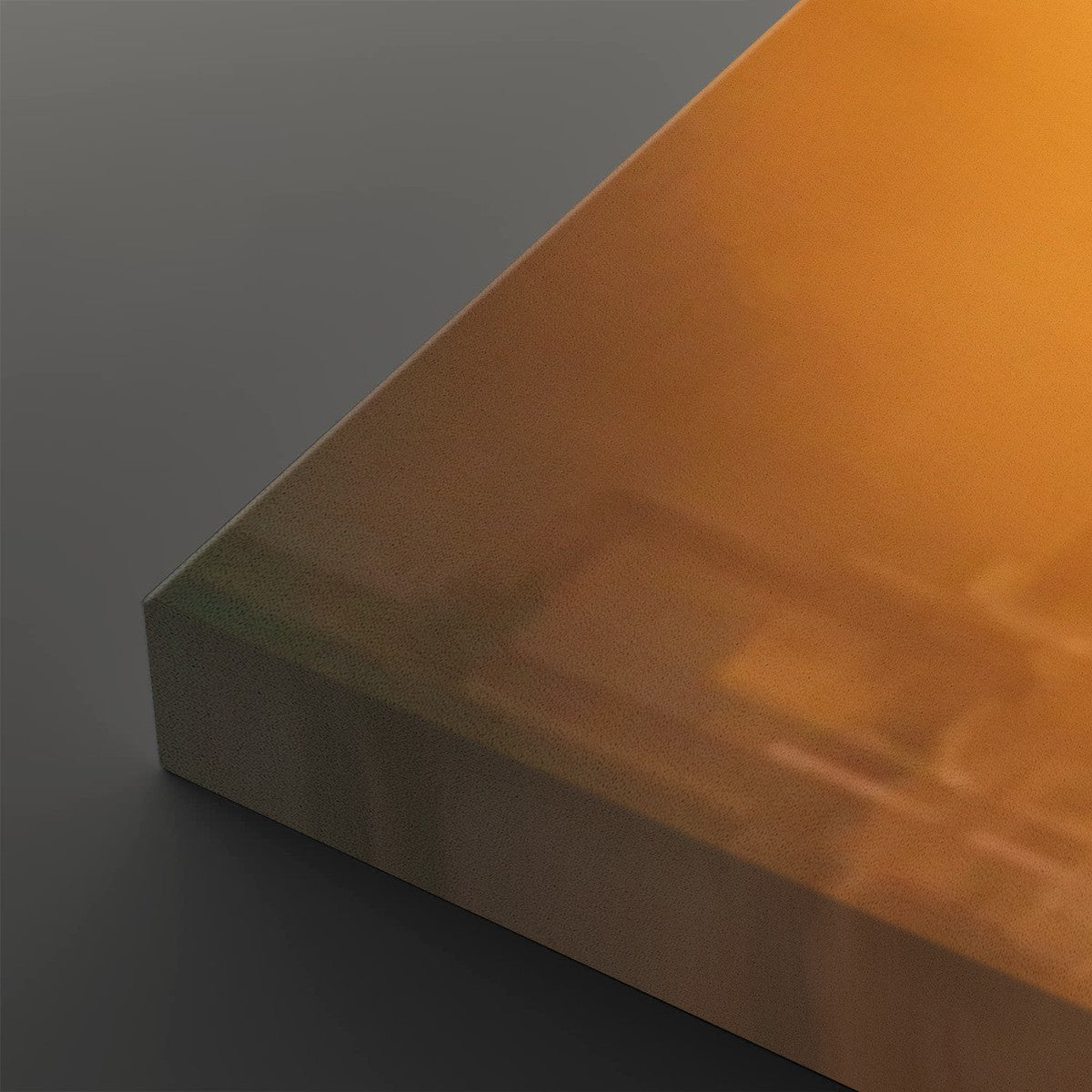 A close-up of a translucent amber-orange acrylic or glass panel with a thick edge, resting on a dark gray surface.