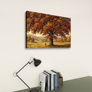 A rectangular wall art print showing an autumn landscape with a large tree of colorful fall leaves, displayed on a light wall above a desk with a black lamp and books.