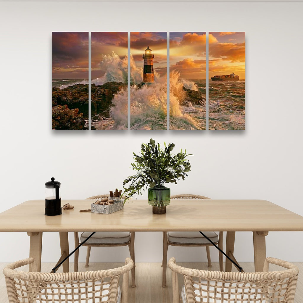 A five-panel canvas wall art set depicting a dramatic lighthouse scene with crashing waves and a golden sunset, displayed on a white wall above a dining table with chairs and a vase.