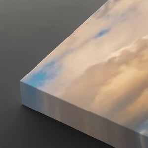 A close-up of a rectangular canvas or panel with a soft marbled sky-like print in pale blue, cream, and warm beige tones, shown against a dark gray background.