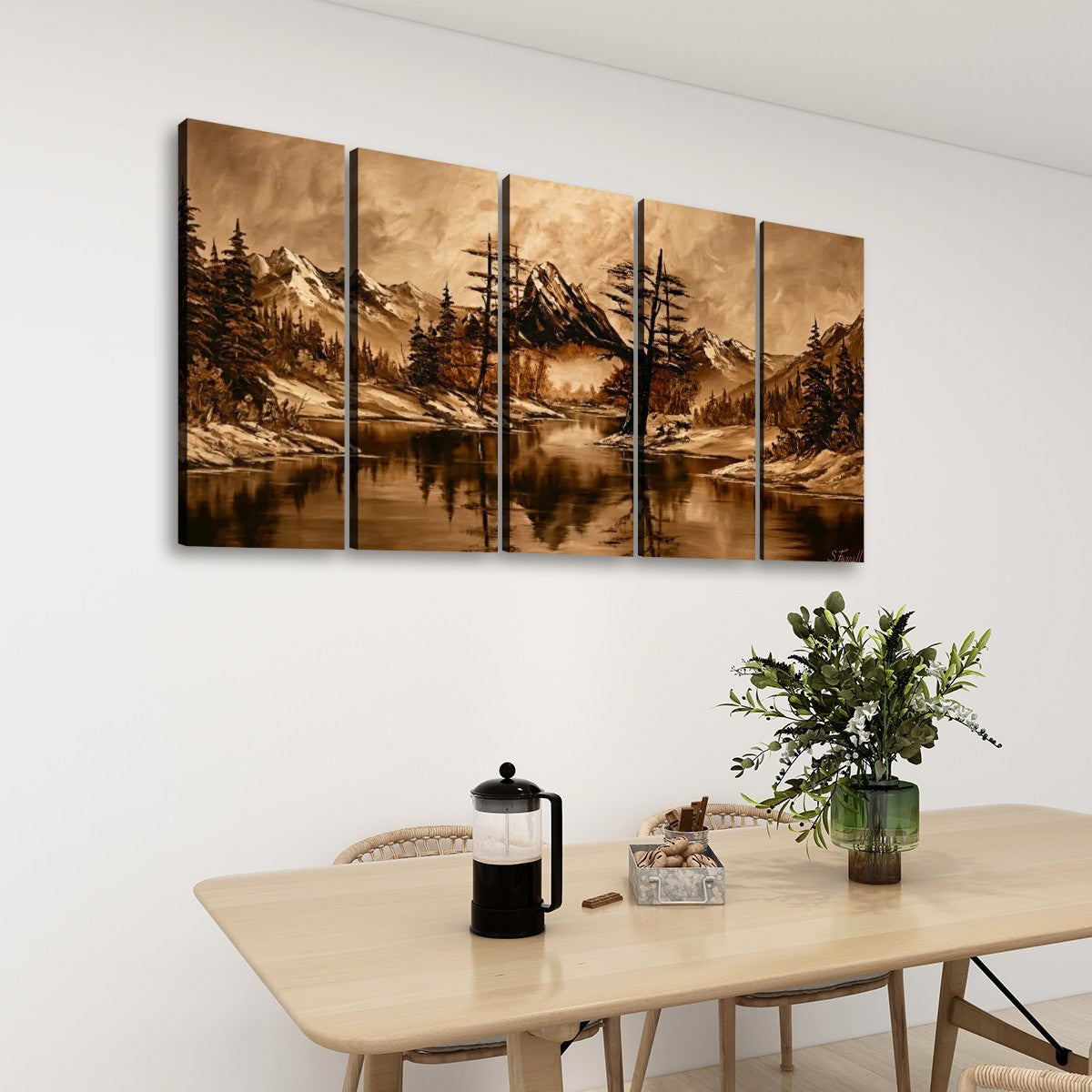 A five-panel canvas wall art set depicting a scenic mountain lake landscape in warm sepia tones, displayed on a white wall above a dining table with chairs, a French press, and a green plant.