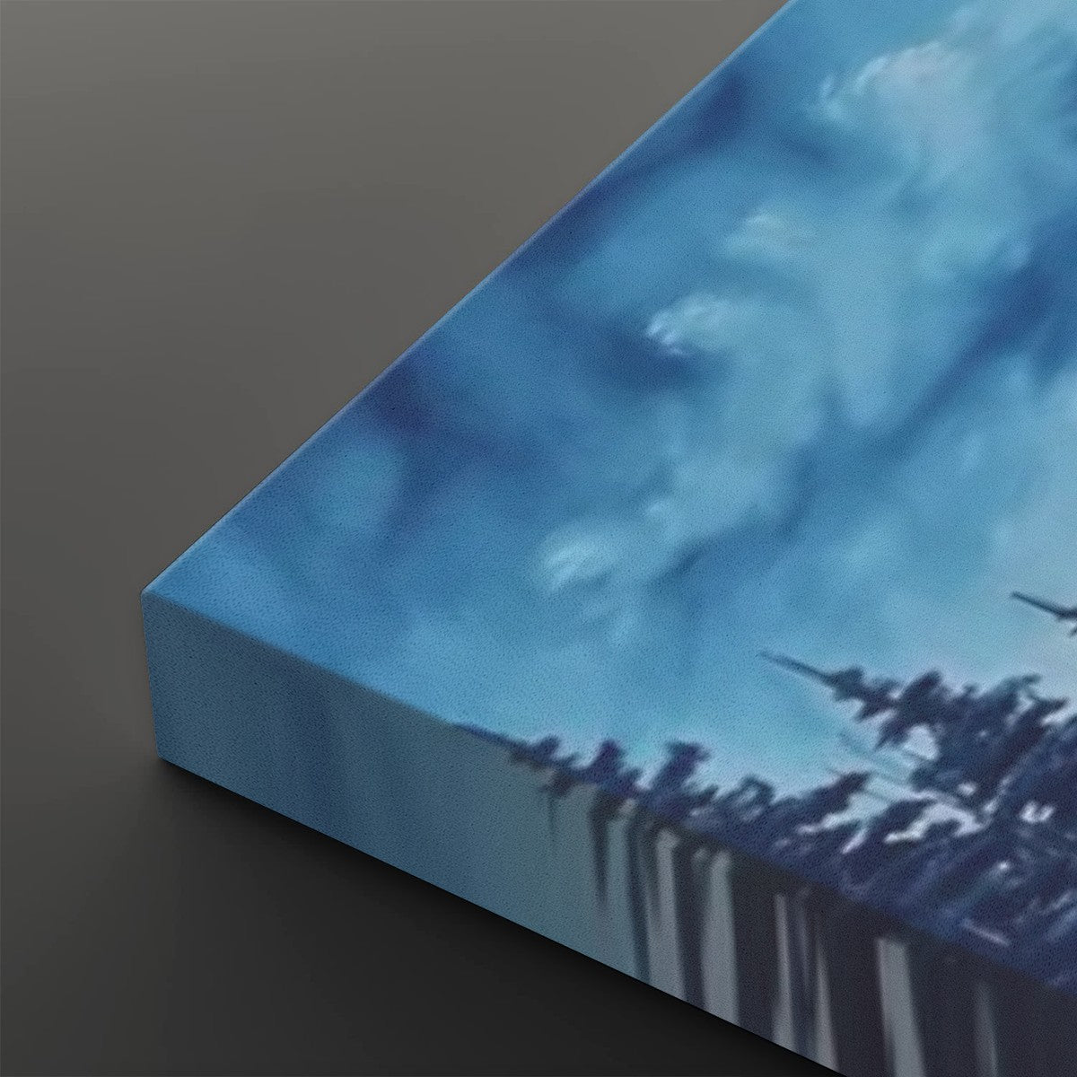 A close-up of a square canvas print showing its wrapped edge, painted with an abstract blue sky and dark tree silhouettes, set against a dark gray background.