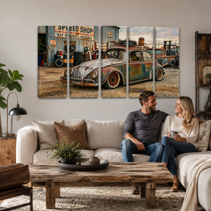 A 4-panel canvas wall art set depicting a vintage rusted VW Beetle in a speed shop, displayed on a light gray wall above a living room sofa with a couple sitting on the couch.