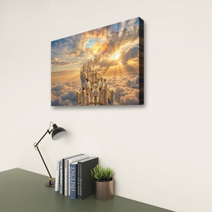 A rectangular wall art canvas showing a golden sunlit sky with clouds and a glowing architectural scene, displayed on a light wall above a desk with books, a lamp, and a small plant.