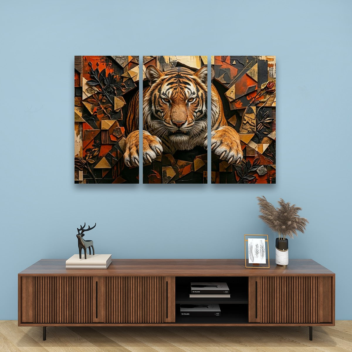 A three-panel canvas wall art set depicting a stylized tiger in warm geometric tones, displayed above a wooden console table against a light blue wall.