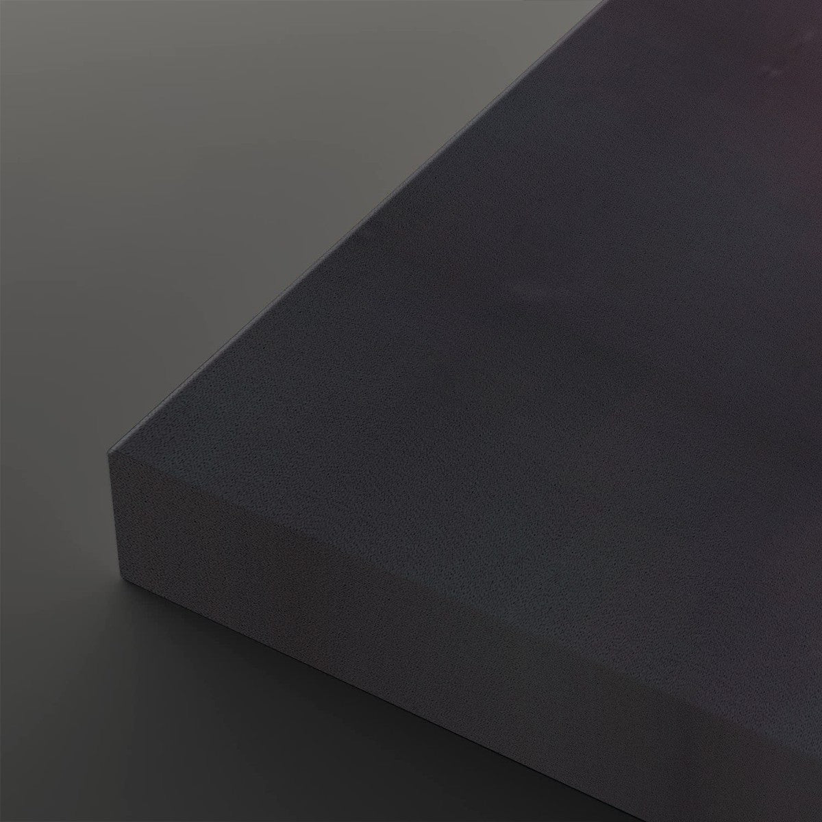 A close-up studio shot of a dark charcoal gray rectangular block or panel corner, showing a matte textured surface and a smooth gray background.