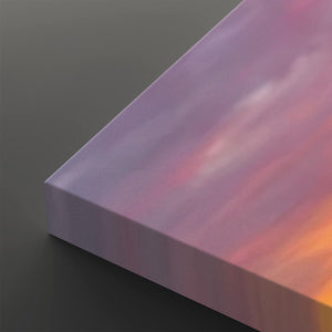 A close-up of a rectangular canvas or panel with a pastel sunset sky design, showing pink, purple, and orange tones, photographed on a dark gray background.