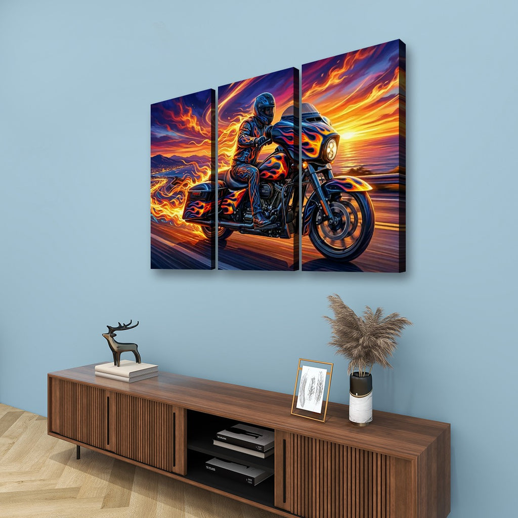 A three-panel canvas wall art set depicting a motorcycle rider on a road at sunset, displayed on a light blue wall above a wooden console table with decorative items.