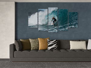 Five-panel wall art of a surfer on a wave above a gray sofa with patterned cushions.