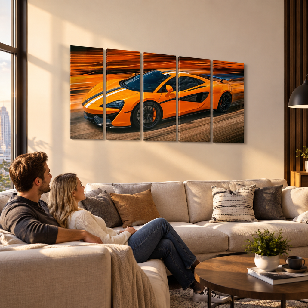 A couple sits on a beige sectional sofa in a modern living room, looking at a five-panel canvas wall art print depicting an orange sports car racing on a track against a warm sunset sky.