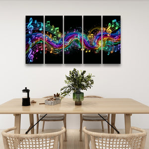 A 4-panel canvas wall art set featuring vibrant, colorful musical notes and treble clefs flowing across a black background, displayed in a modern dining room setting above a wooden table with chairs.