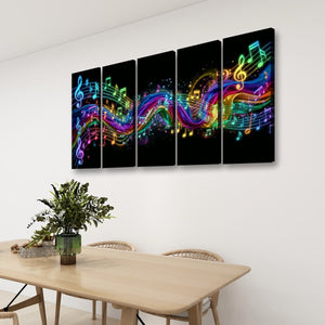 A four-panel canvas wall art set hanging above a light wood dining table in a modern room. The artwork features glowing multicolored musical notes and staff lines on a black background.