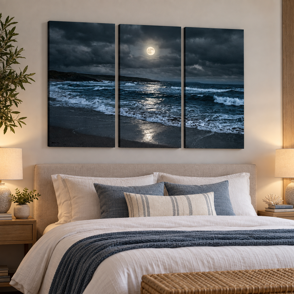 A three-panel canvas wall art set depicting a dramatic moonlit beach scene with dark stormy clouds, ocean waves, and moonlight reflection, displayed above a neatly made bed in a styled bedroom.