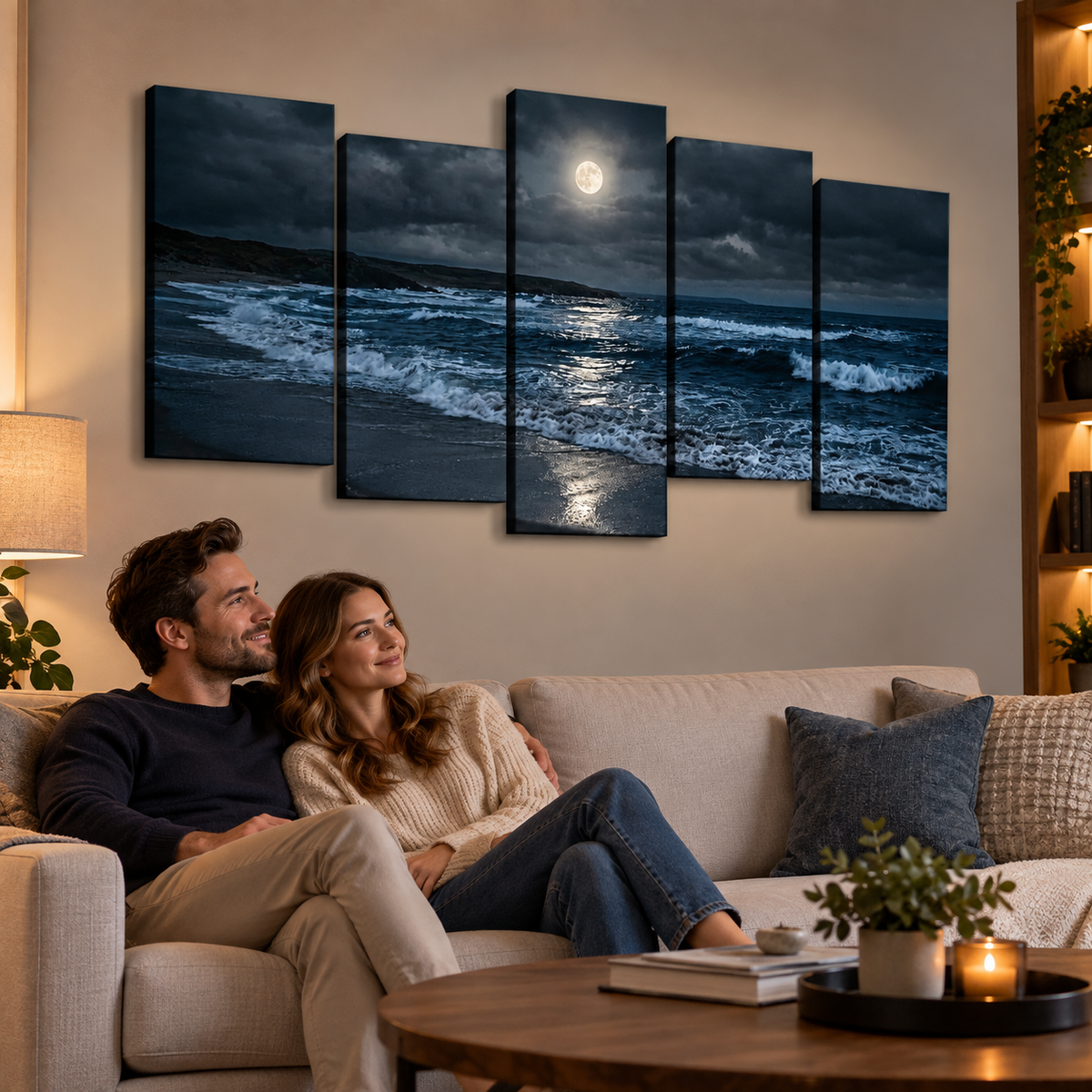 A couple sits on a beige sofa in a warmly lit living room, looking at a five-panel canvas wall art set depicting a dramatic moonlit ocean scene with dark blue waves and a bright full moon.