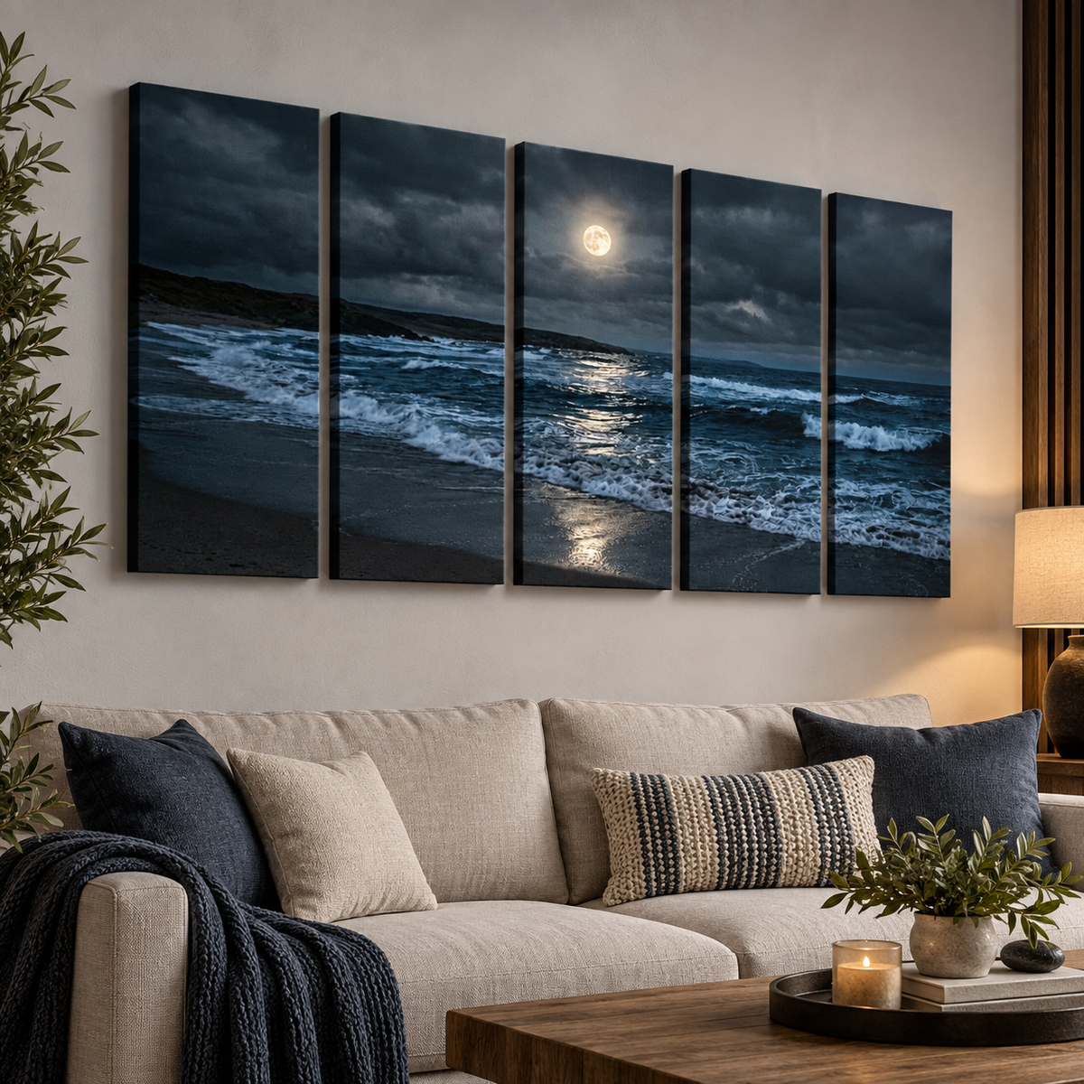 A five-panel canvas wall art set depicting a dramatic moonlit beach scene with dark waves, stormy clouds, and bright moonlight reflection, displayed above a beige sofa in a modern living room setting.