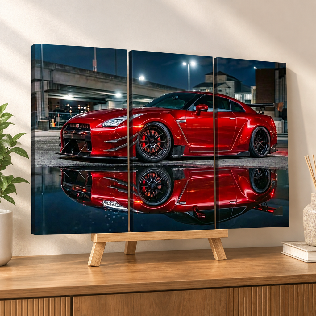 A three-panel canvas wall art print showing a red sports car reflected in water, displayed on a wooden stand on a console table in a styled room.
