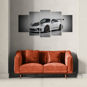 Five-panel wall art of a white porsche 911 gt3 991.2 generation sports car on a gray wall above an orange sofa.