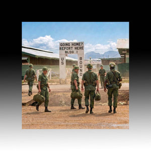 Group of soldiers walking towards a sign indicating they are going home at a military base.