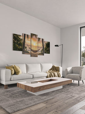 Modern living room with a white sofa, wooden coffee table, and wall art depicting a sunset.