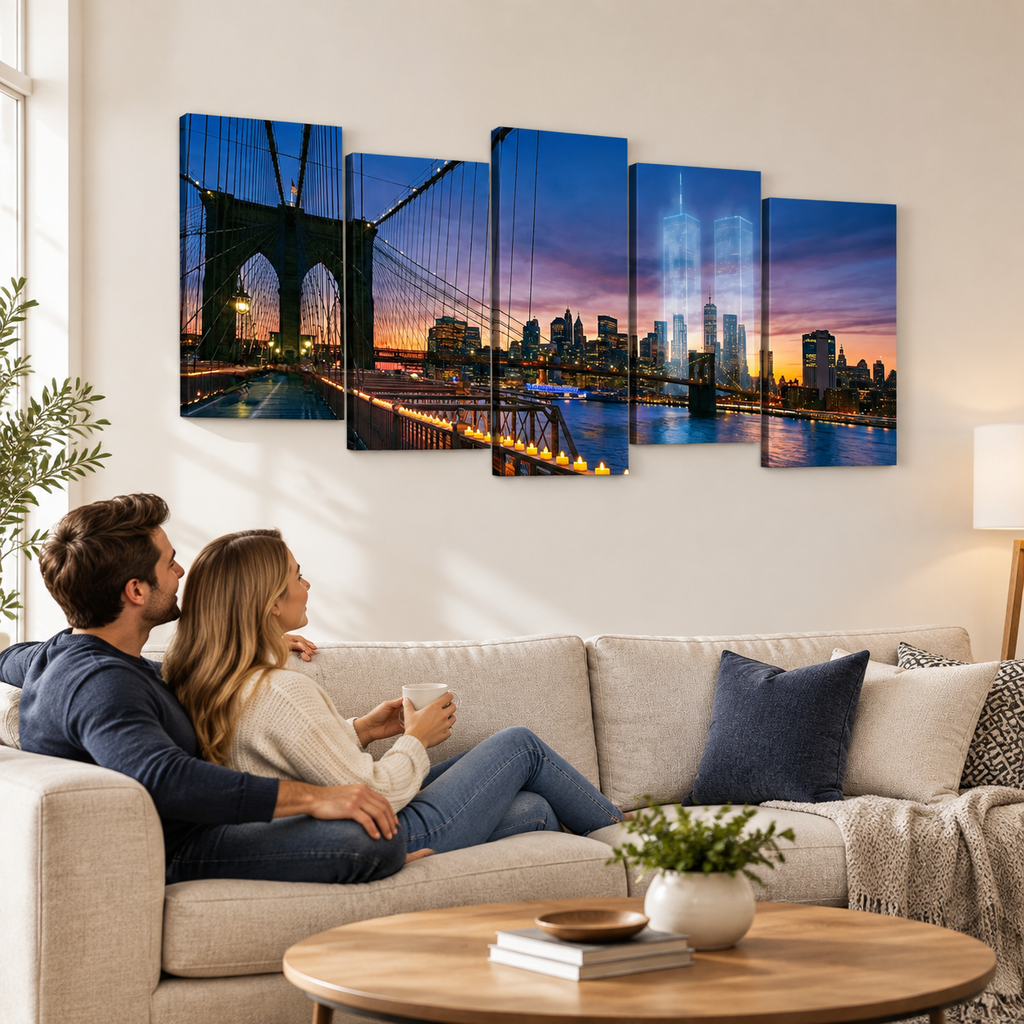 A five-panel canvas wall art set depicting the Brooklyn Bridge and New York City skyline at dusk, displayed above a beige sofa in a modern living room with a couple sitting on the couch.